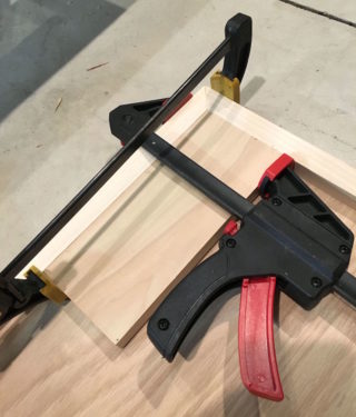 Clamping and gluing the headboard pieces together with scrap wood in the edges