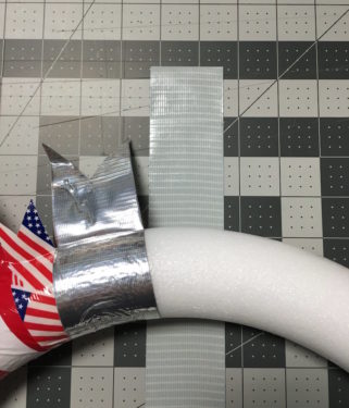 Wreath form placed onto a piece of silver duck tape with the sticky side up