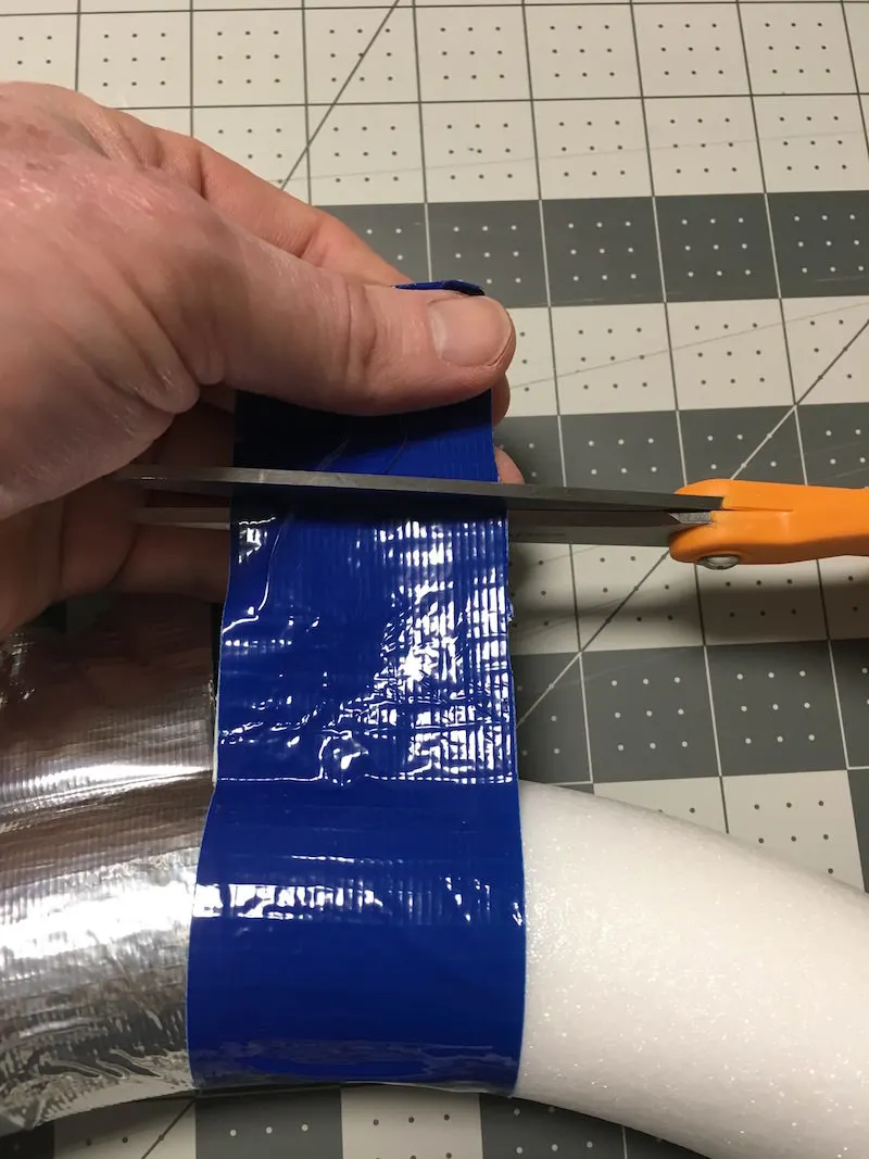 Cutting across the top of the blue tape with scissors