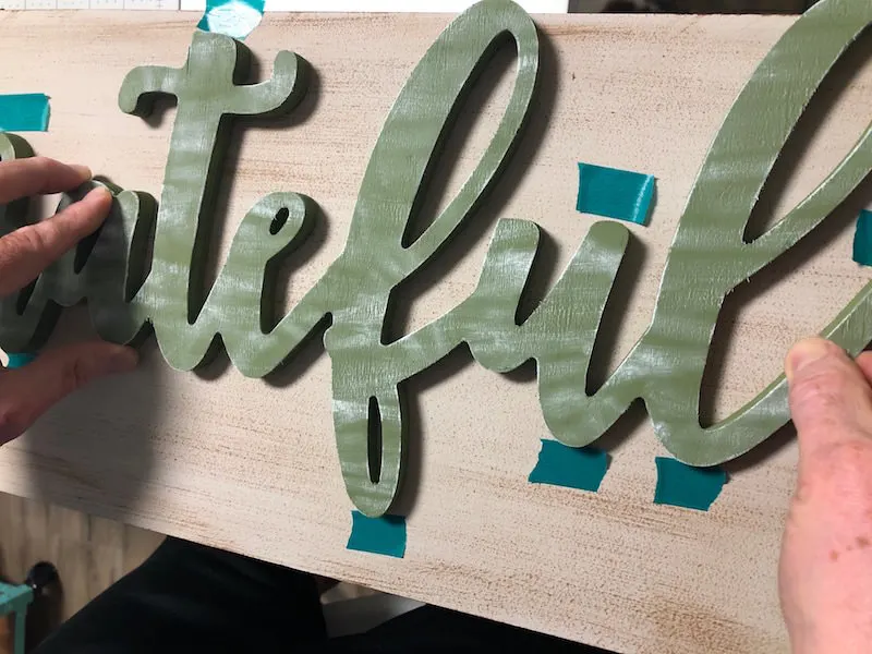 Glue down a wood word onto a Thanksgiving sign