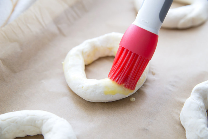 Rubbing butter onto the bagels with a silicone brush