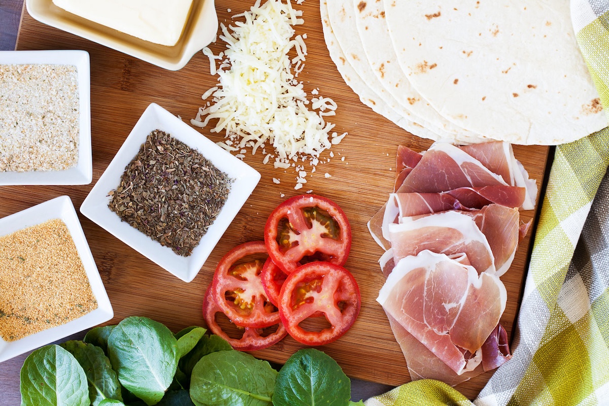 tortilla, mozzarella cheese, tomato, garlic salt, spices, kale, prosciutto, and butter