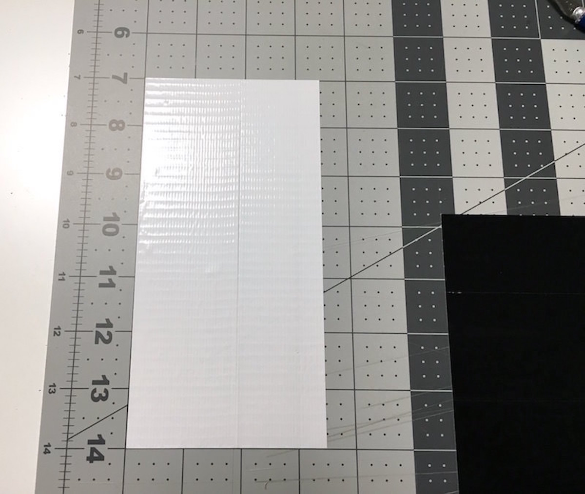 Two white strips of duct tape on a craft mat