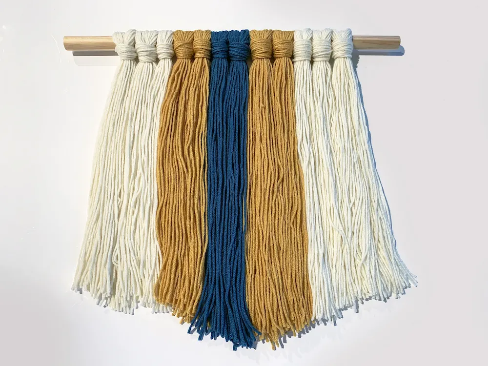 DIY yarn wall hanging laying on a white background