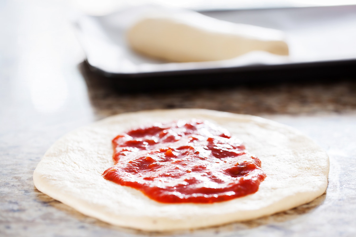 tomato sauce spread onto dough