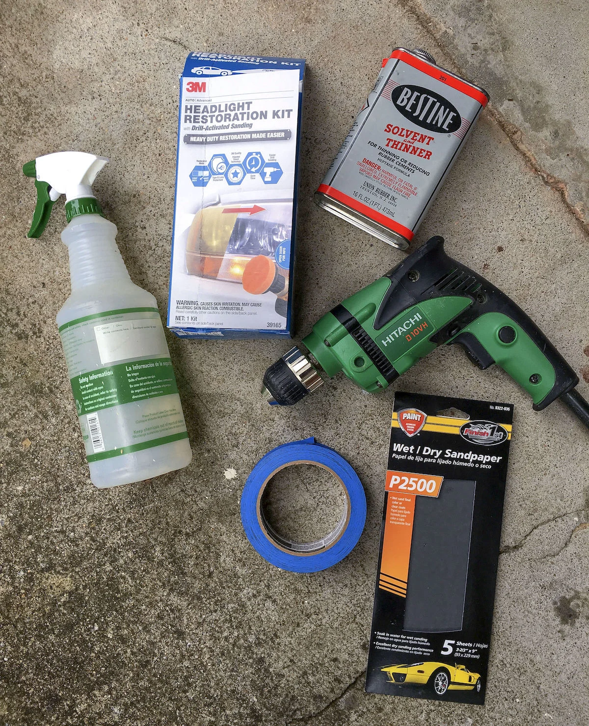 3M headlight restoration kit, Bestine Solvent and thinner, Hitachi drill, wet/dry sandpaper, painter's tape, and a spray bottle