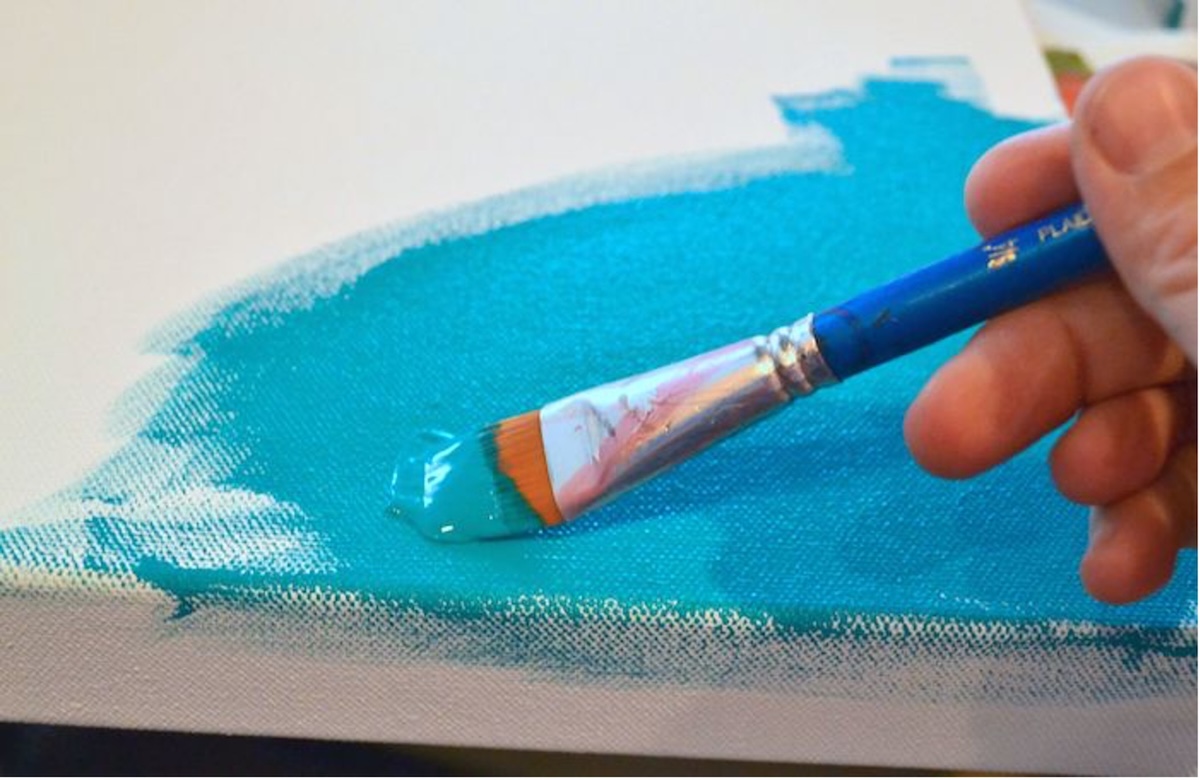 Painting the canvas with turquoise paint