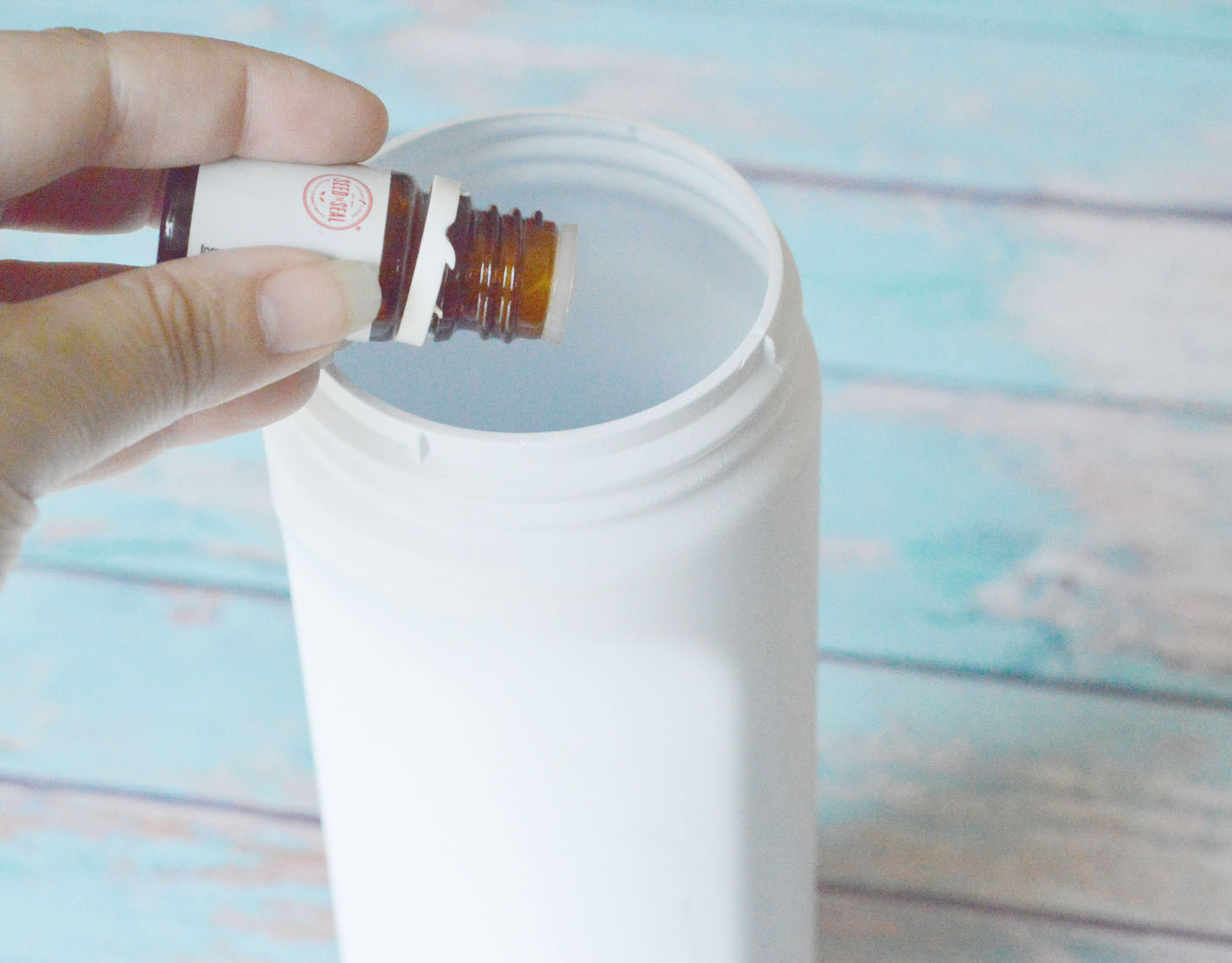 Putting essential oil drops in the container with baking soda