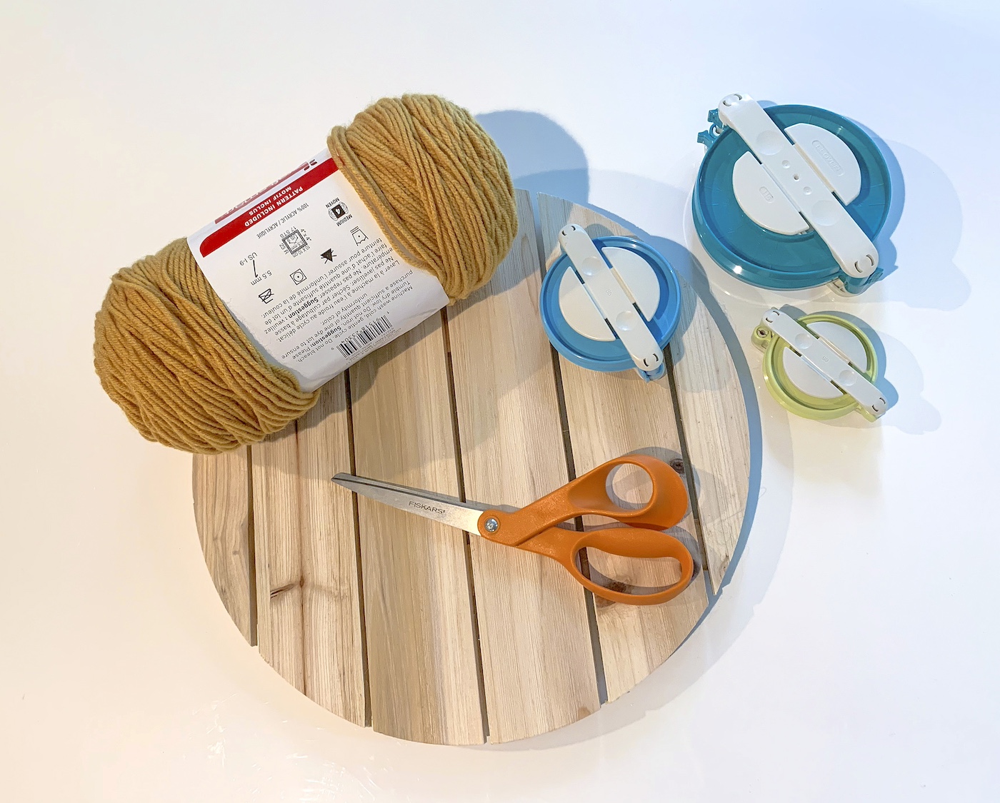 Wood plaque with scissors, pom pom makers, and yarn