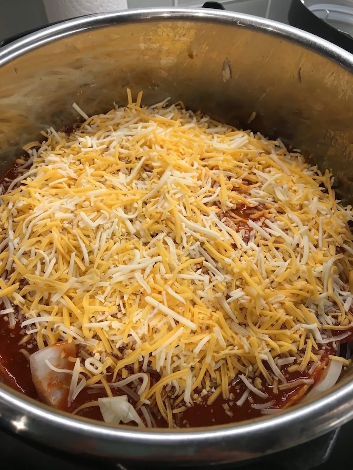 Cheese, onion, and enchilada sauce layered in the instant pot