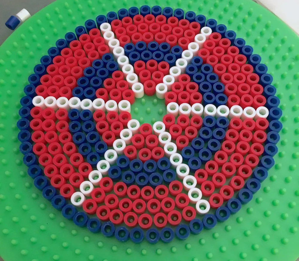 Red white and blue perler beads on a round pegboard