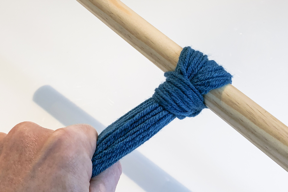 Hand-tightening-a-loop-of-yarn-to-a-dowel-rod