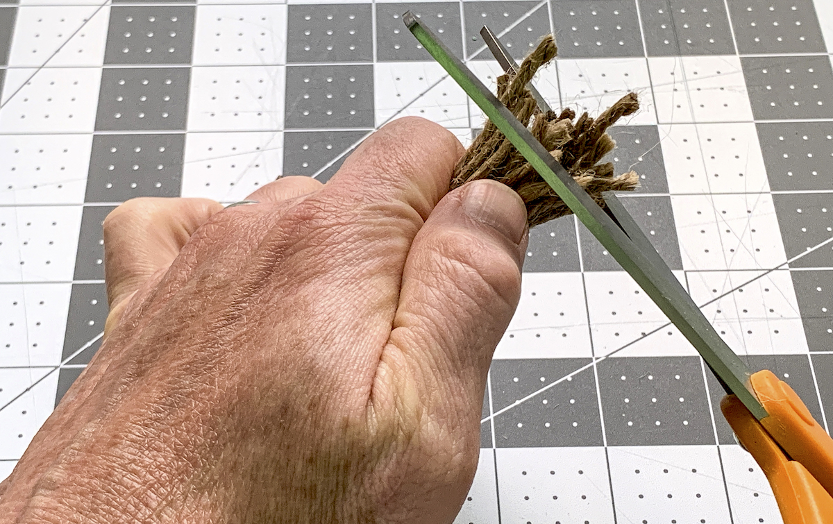Trimming the end of a jute tassel with scissors