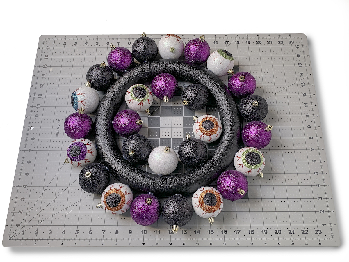 Black painted wreath form with Halloween ornaments glued to the inside and outside