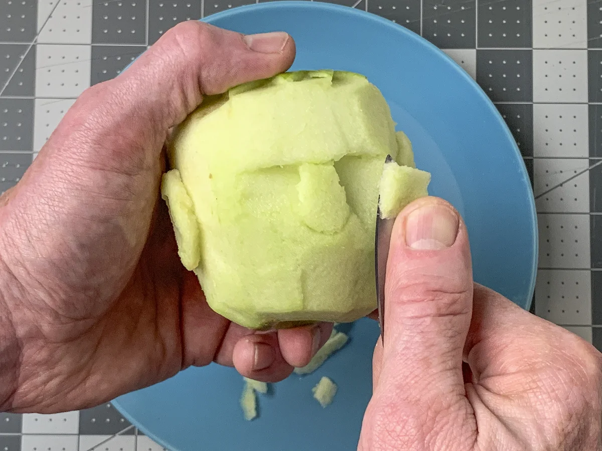 Cutting out cheek pieces on the apple with a knife