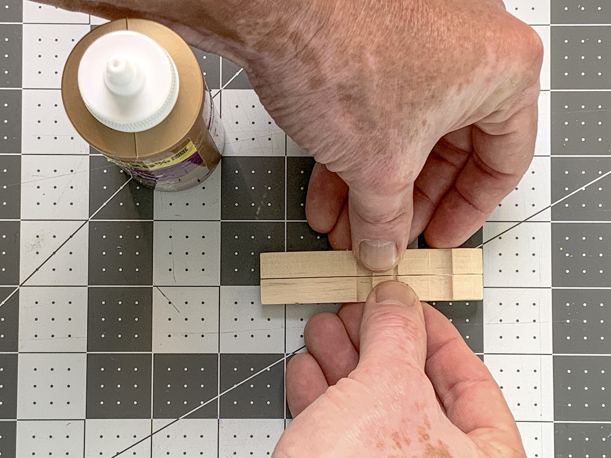 Hand holding two clothespins together with glue