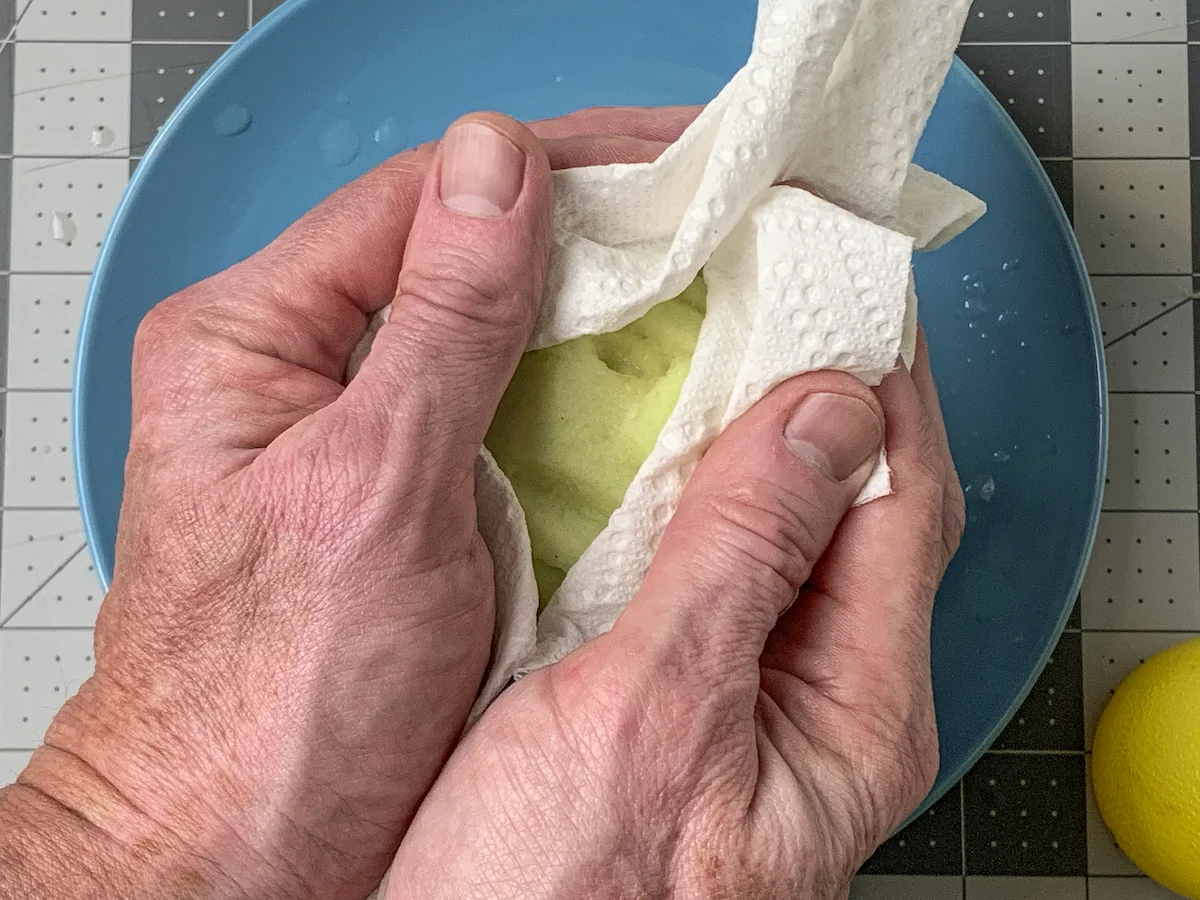 Wiping lemon juice off an apple with a paper towel