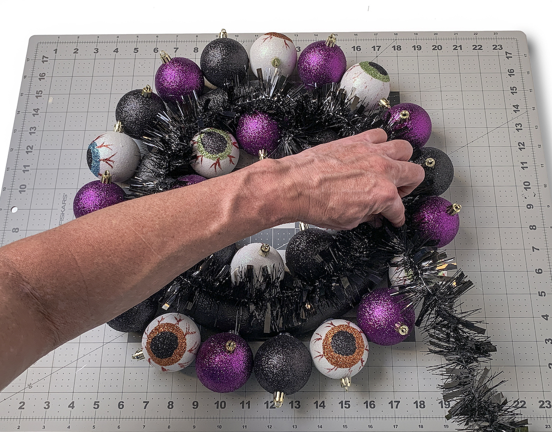 Wrapping black glitter garland around the wreath form