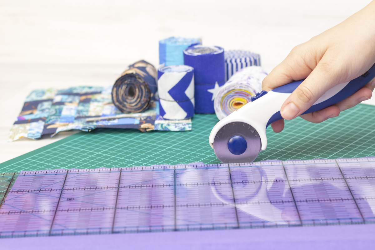 Person-using-a-rotary-cutter-and-quilting-ruler-to-cut-fabric