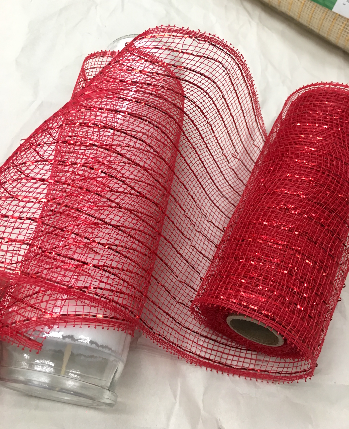 Roll of deco mesh rolled partially around a 12 inch glass candle