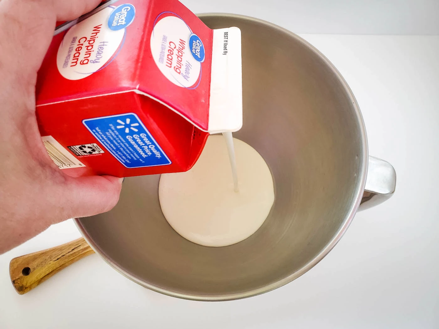Pouring whipping cream into a metal bowl