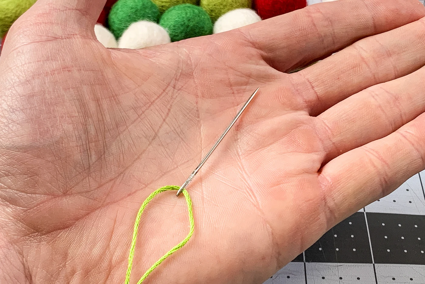 Hand holding a needle strung onto embroidery floss