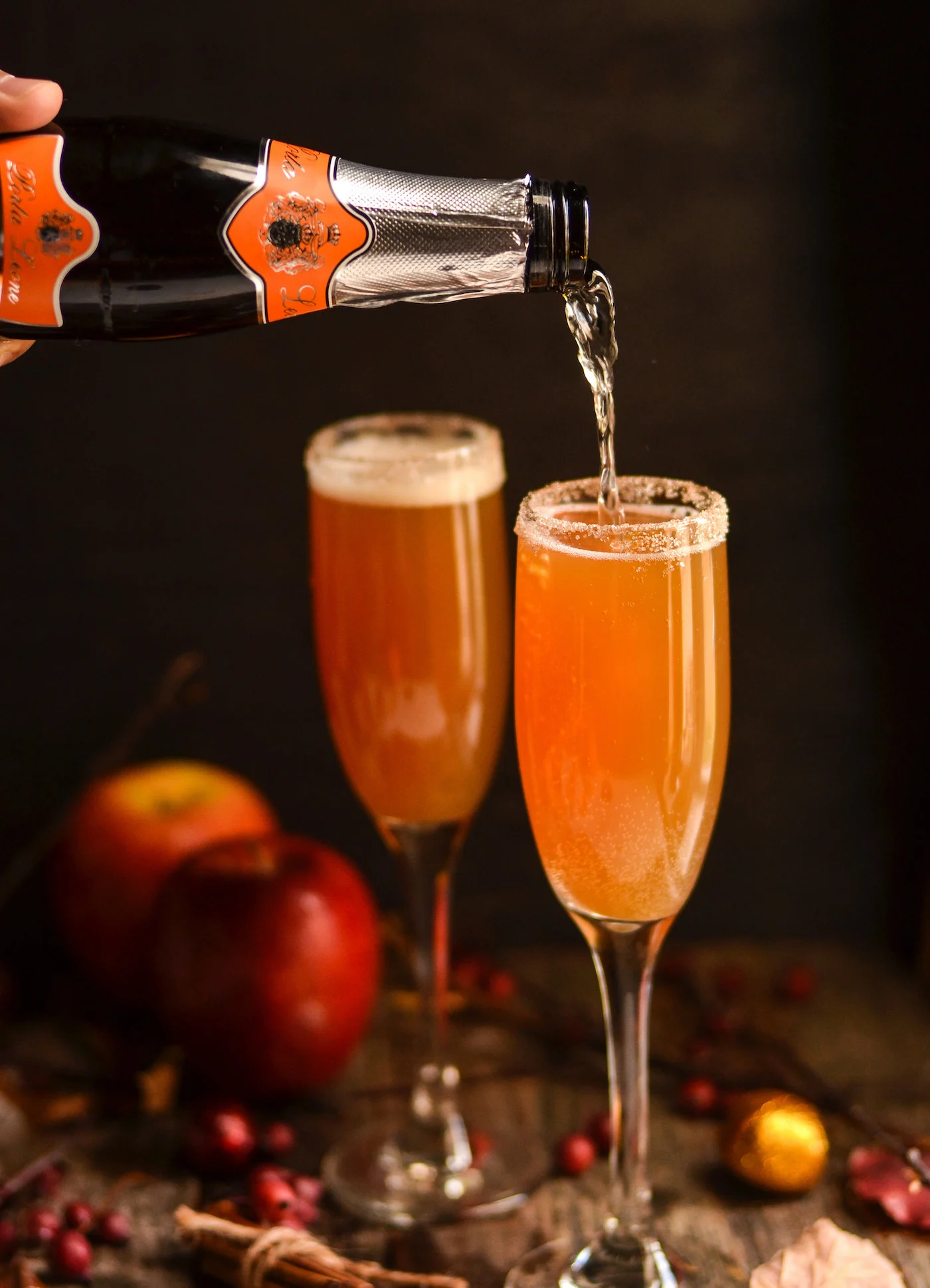 Pouring champagne into a glass with apple cider