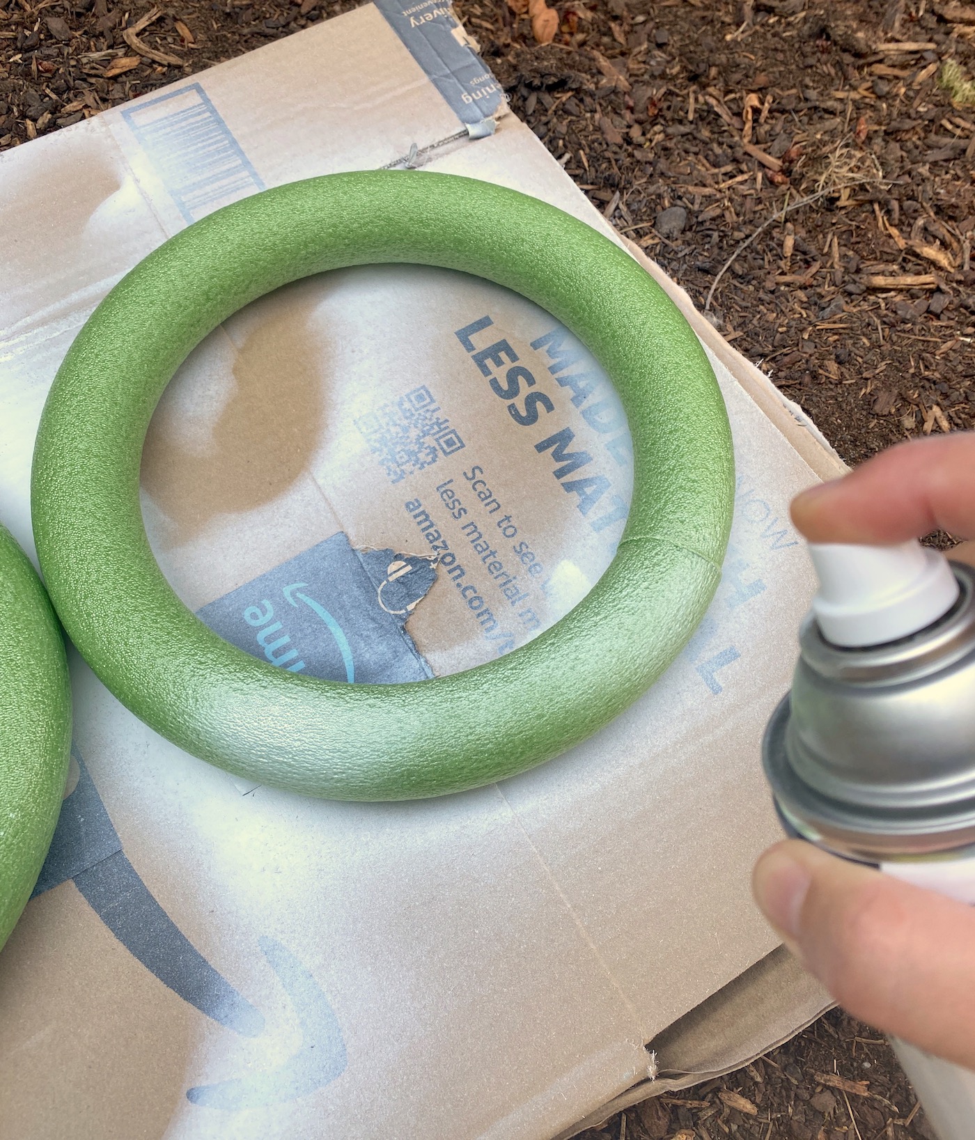 Spray painting a green foam wreath with white spray paint