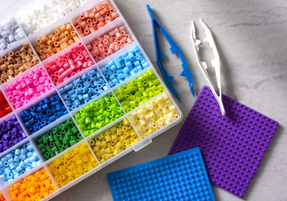 Perler beads in several colors, pegboards, and two sets of plastic tweezers