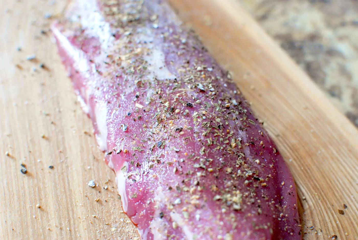 Pork loin sitting on a cutting board with spices