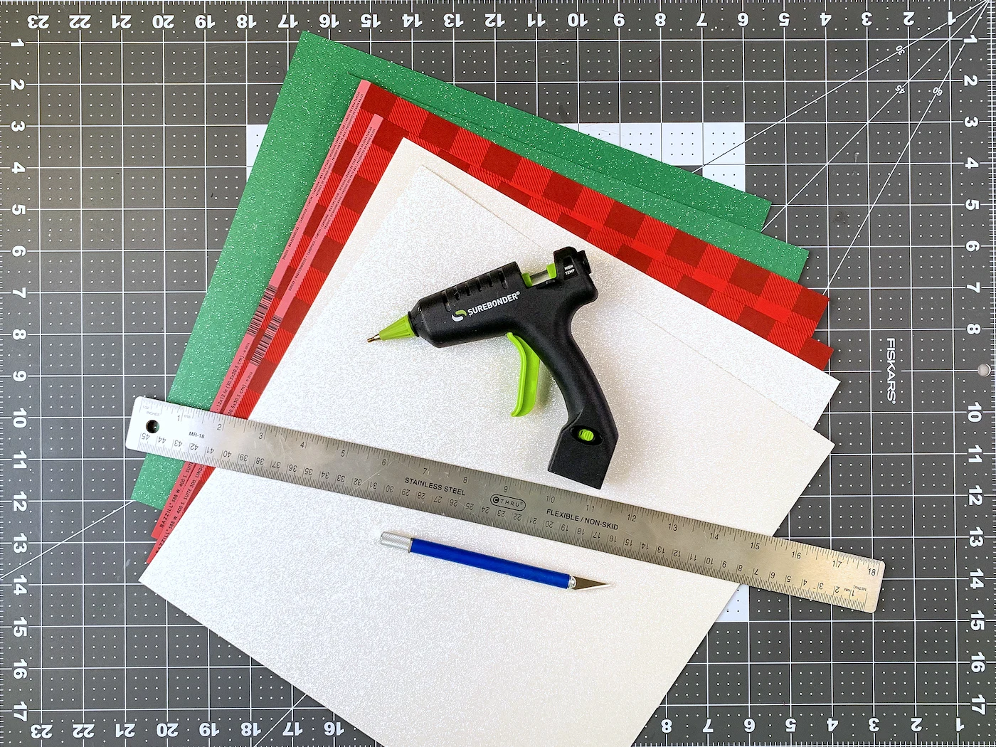 Christmas cardstock, hot glue, ruler, and a craft knife