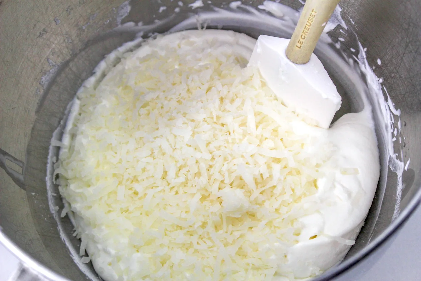 Adding cream of coconut and shredded coconut to the cream