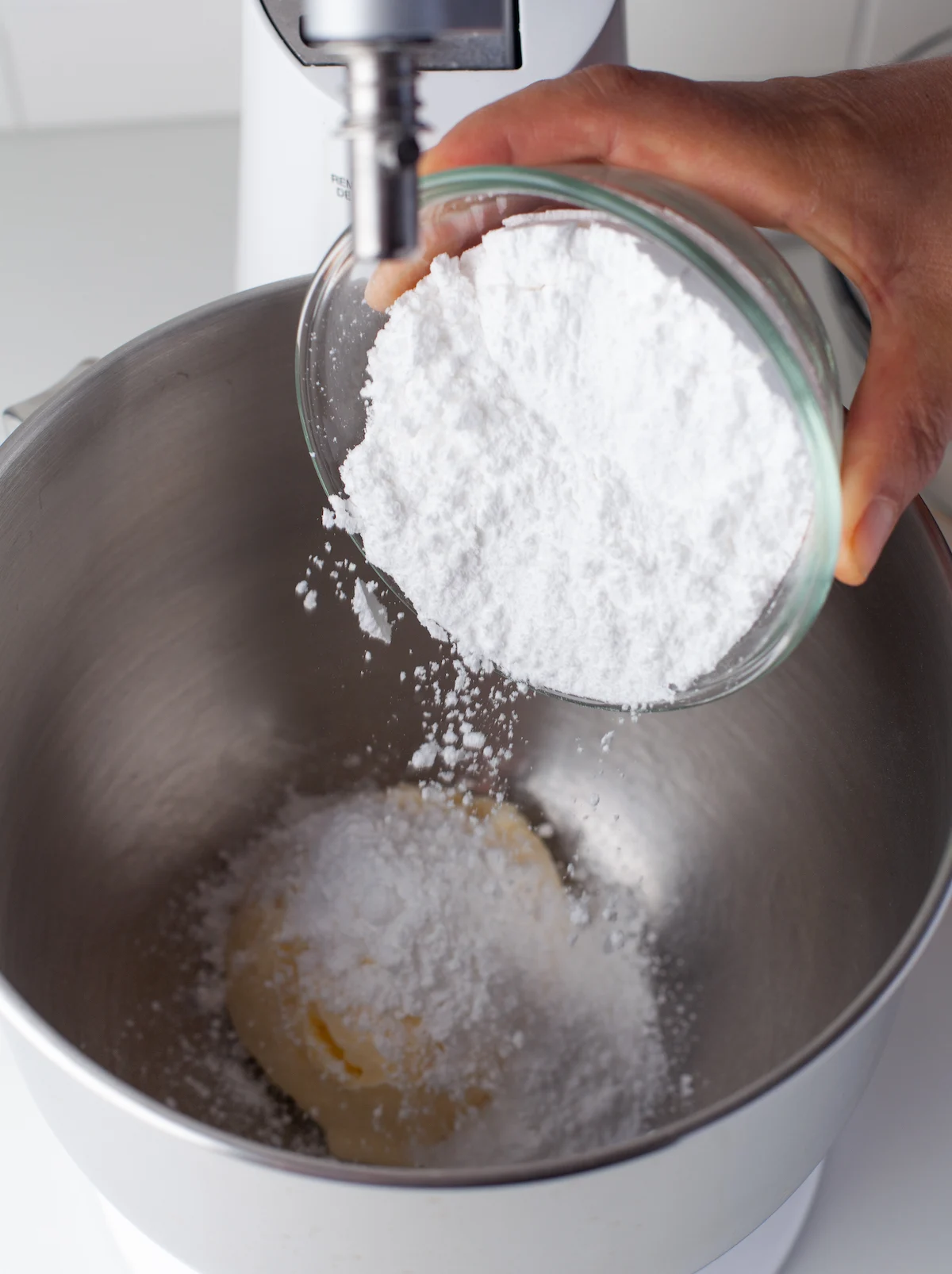Adding powdered sugar to butter in a mixing bowl
