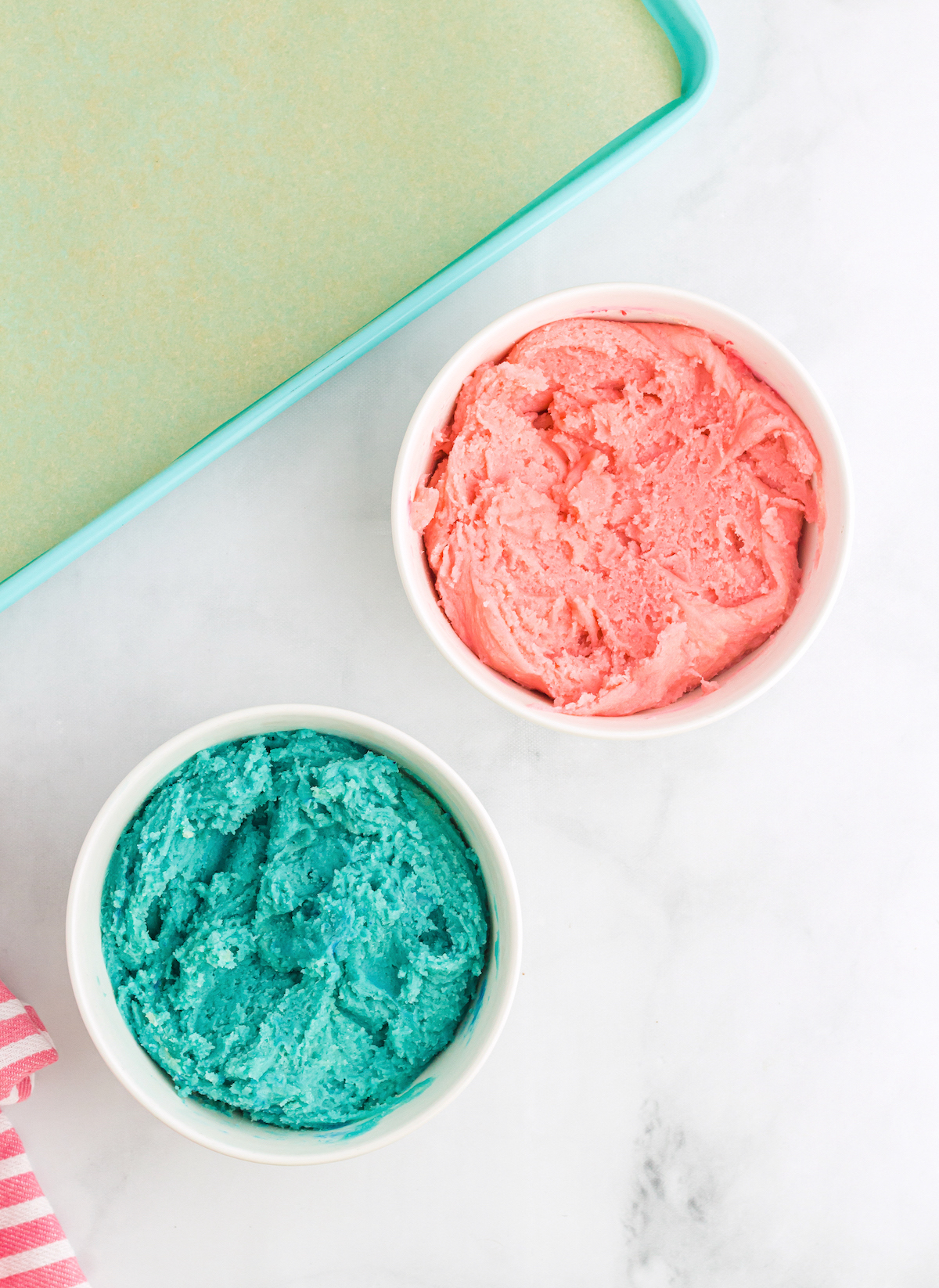 Dough split into two bowls with one colored pink and the other blue