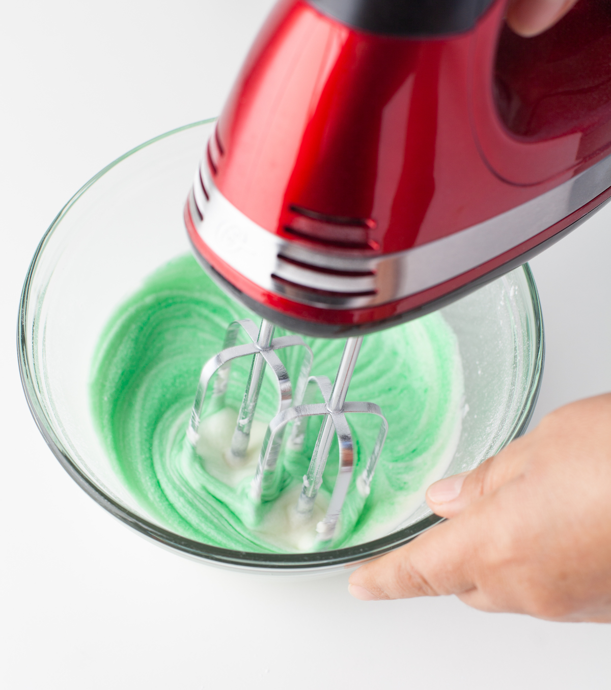 Adding green food coloring to the frosting mixture