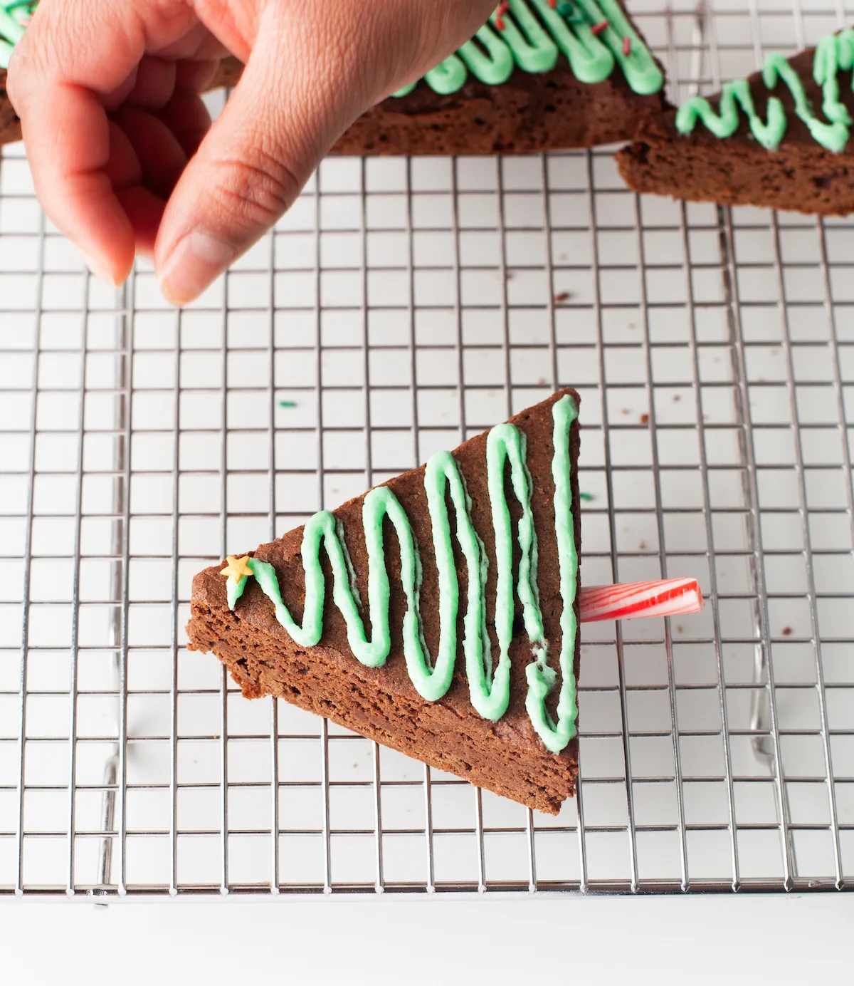 Adding the Christmas sprinkles to the top of the green frosting on the brownie