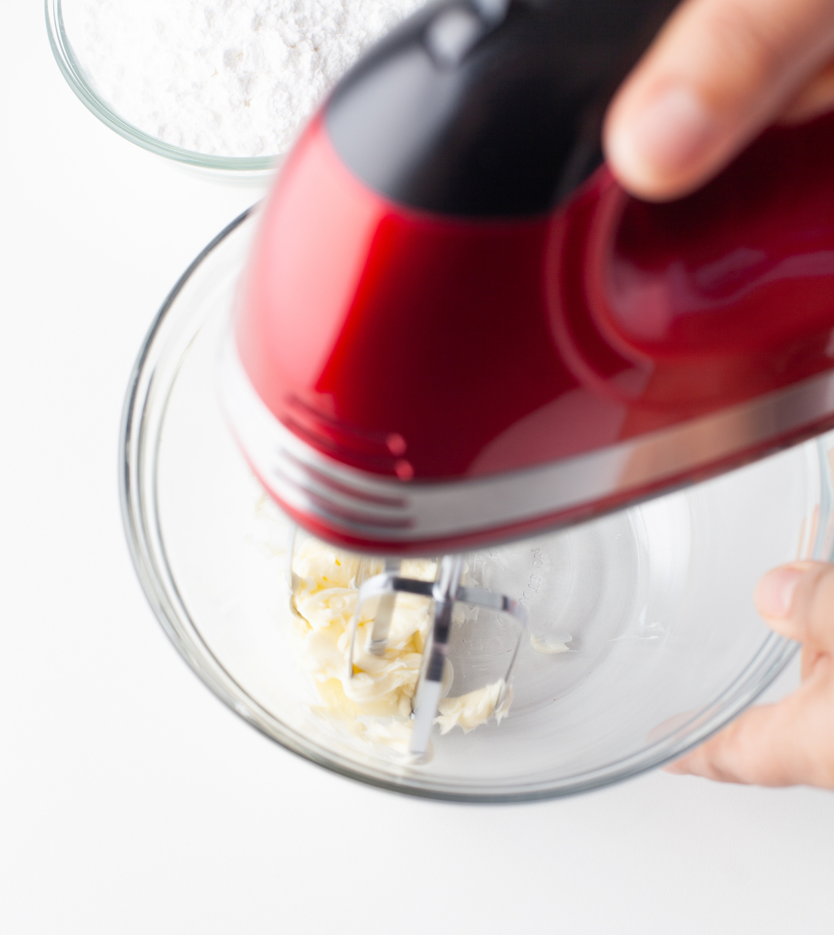 Beating butter with a red mixer in a glass bowl