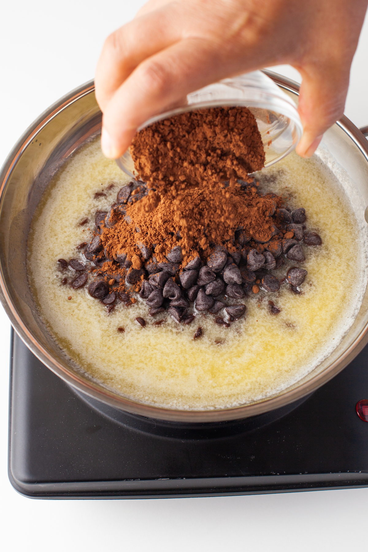 Chocolate chips melting in butter with cocoa powder being added