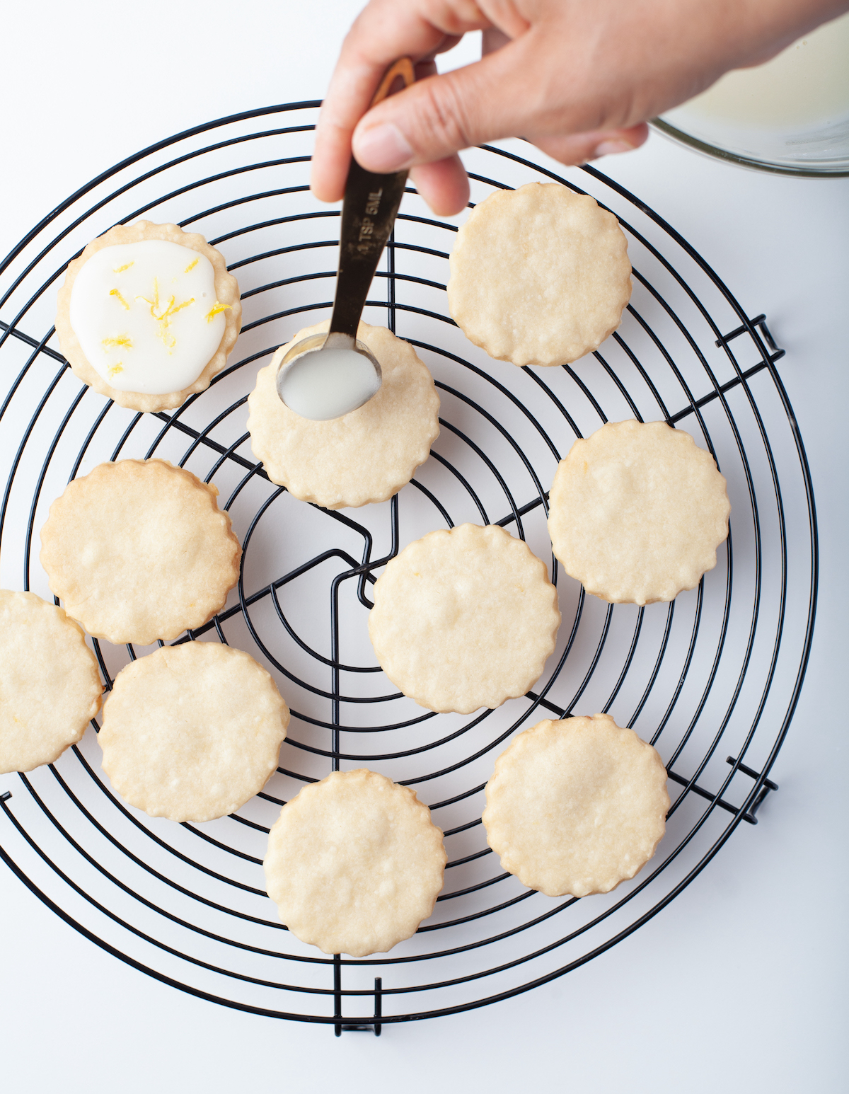 Drizzling the lemon glaze onto the cookies