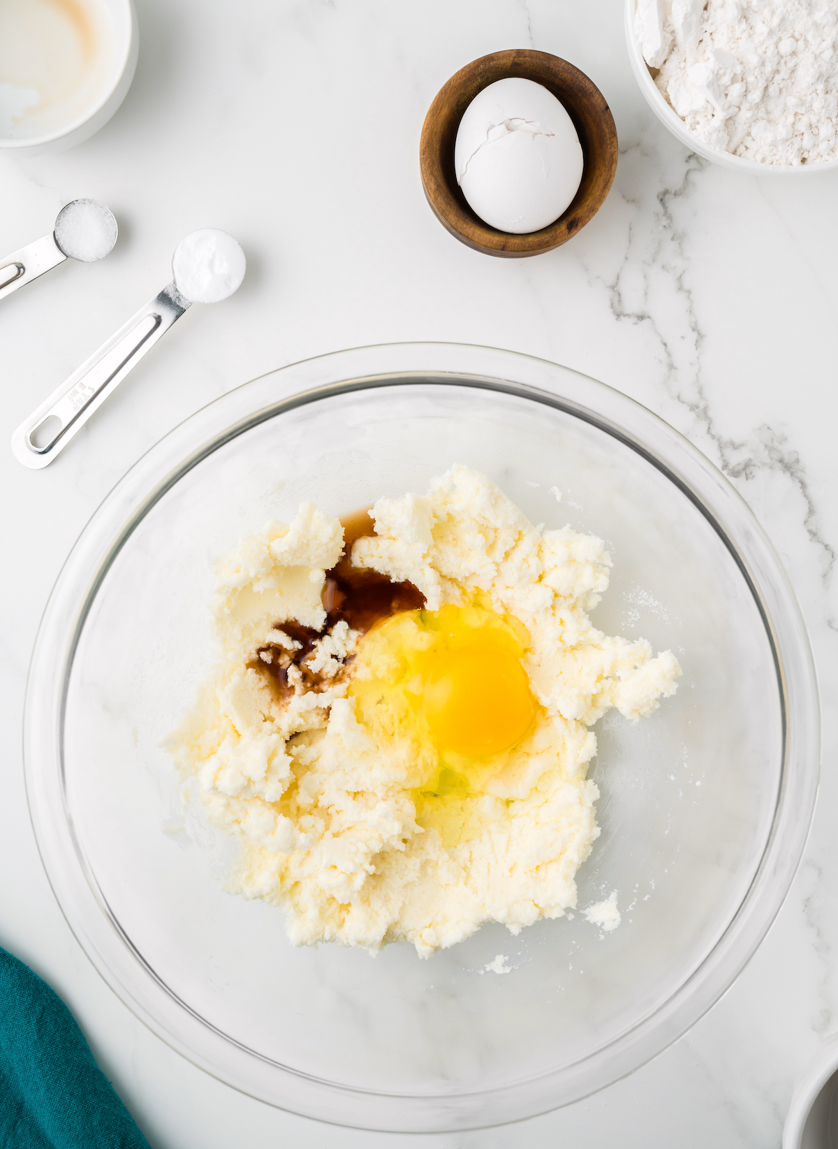 Egg and vanilla added to butter and sugar in a clear glass bowl