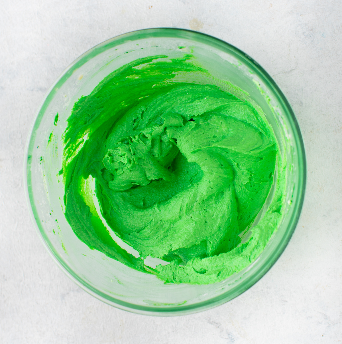 Mixed green icing in a clear glass bowl