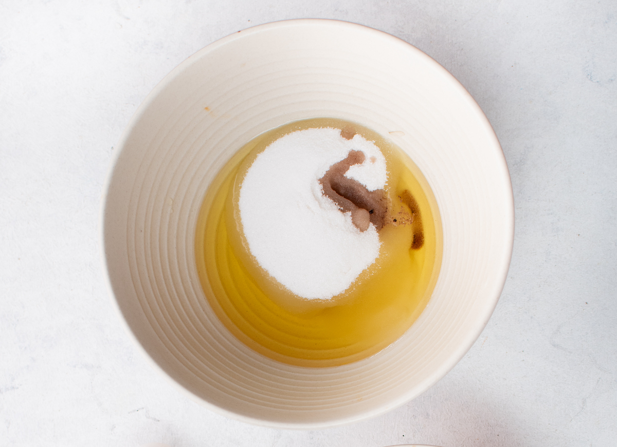 Oil, sugar, and vanilla in a white ceramic bowl