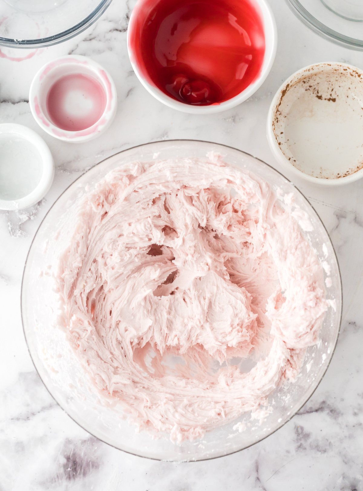 Pink cherry frosting mixed in a glass bowl