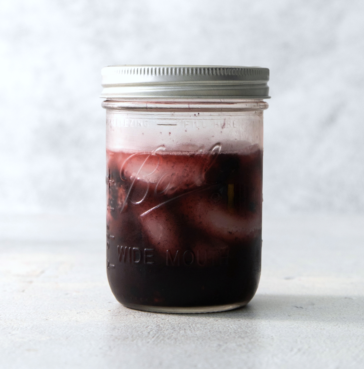 shaking a black widow cocktail in a mason jar