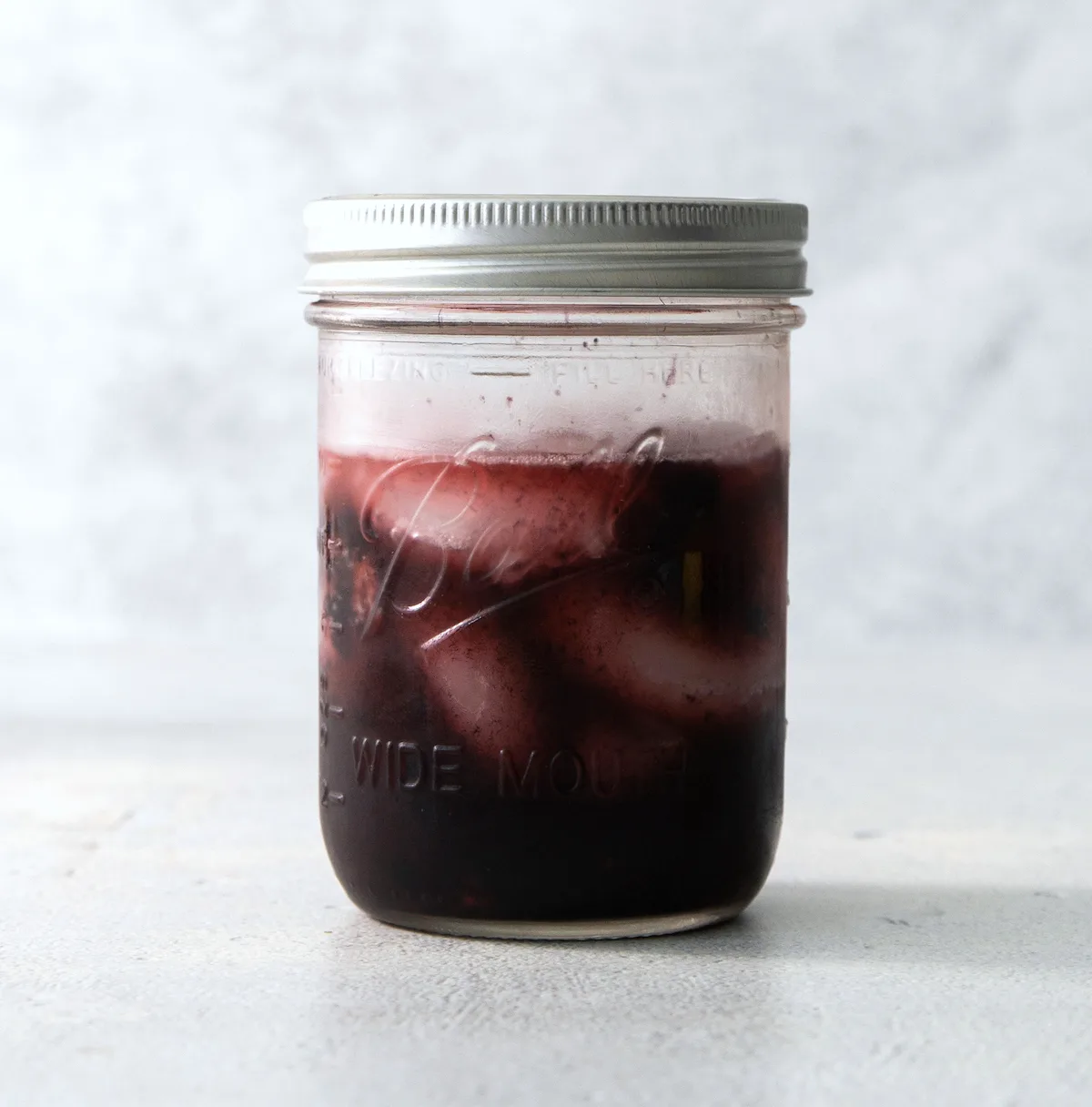 shaking a black widow cocktail in a mason jar