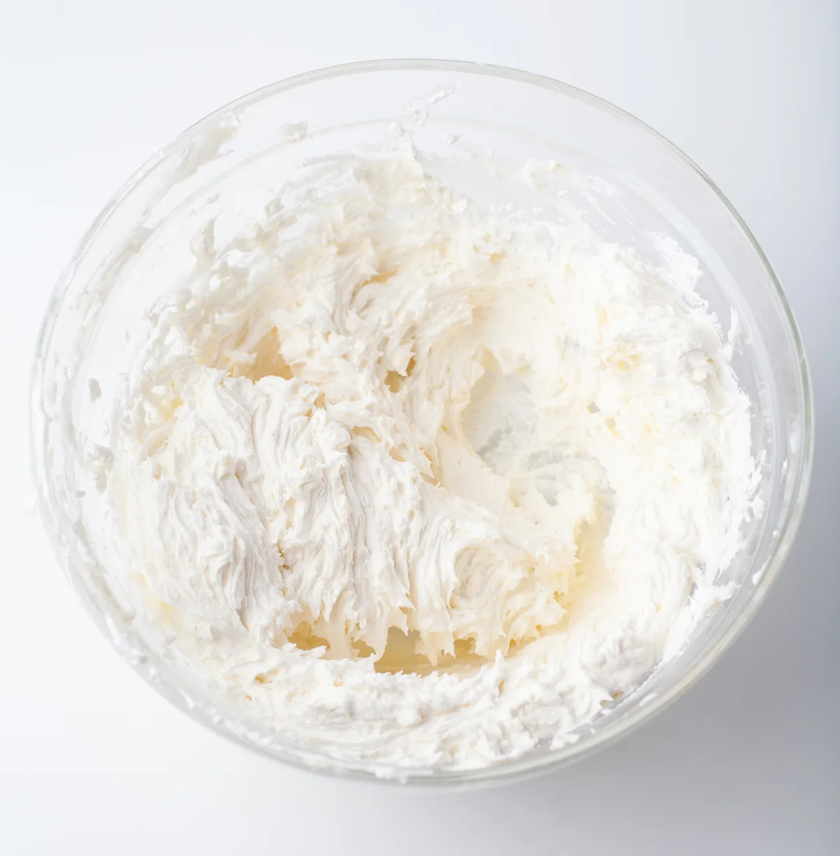 Buttercream frosting mixed in a clear glass bowl