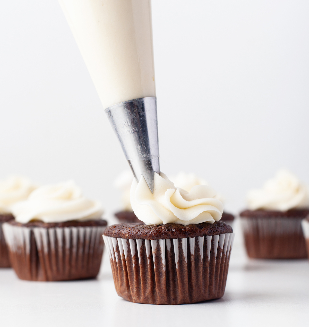 Piping the vanilla frosting onto the cupcakes