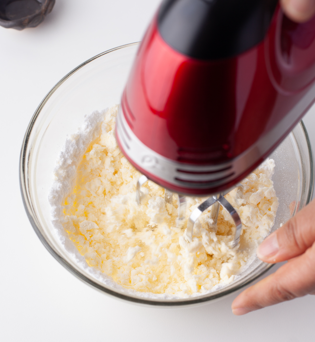Powdered sugar being mixed into the creamed butter with a mixer