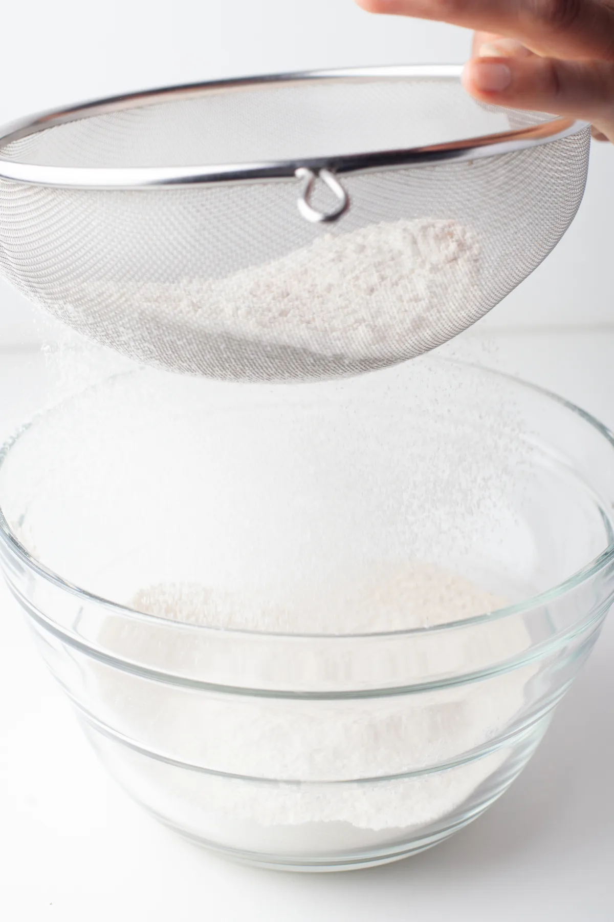 Sifting flour into a clear glass bowl