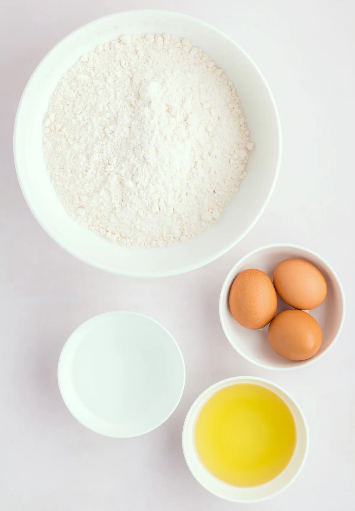 dry ingredients in one bowl with water, eggs, and oil in separate bowls